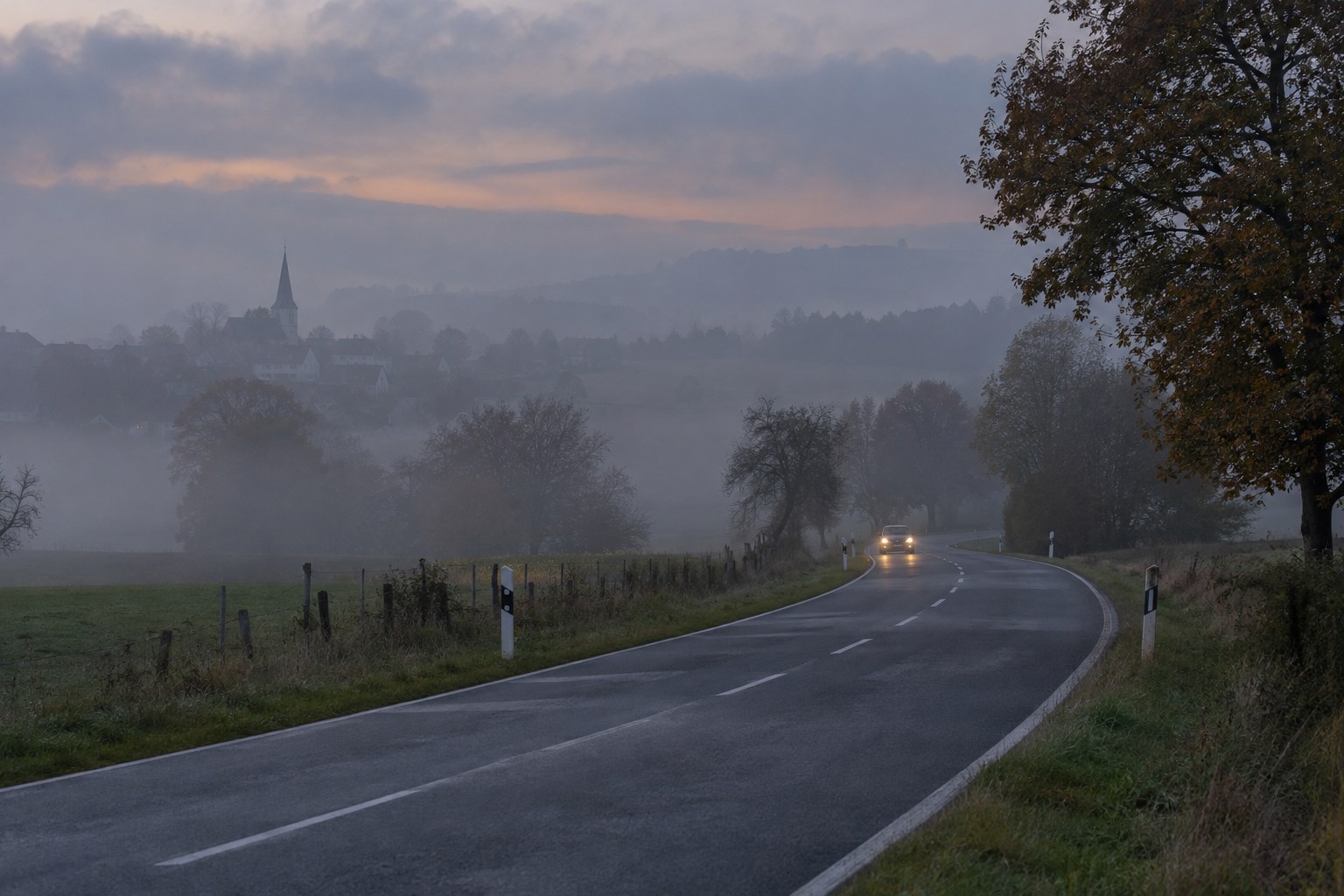 Straße mit geringer Sicht in einer Nebellandschaft.