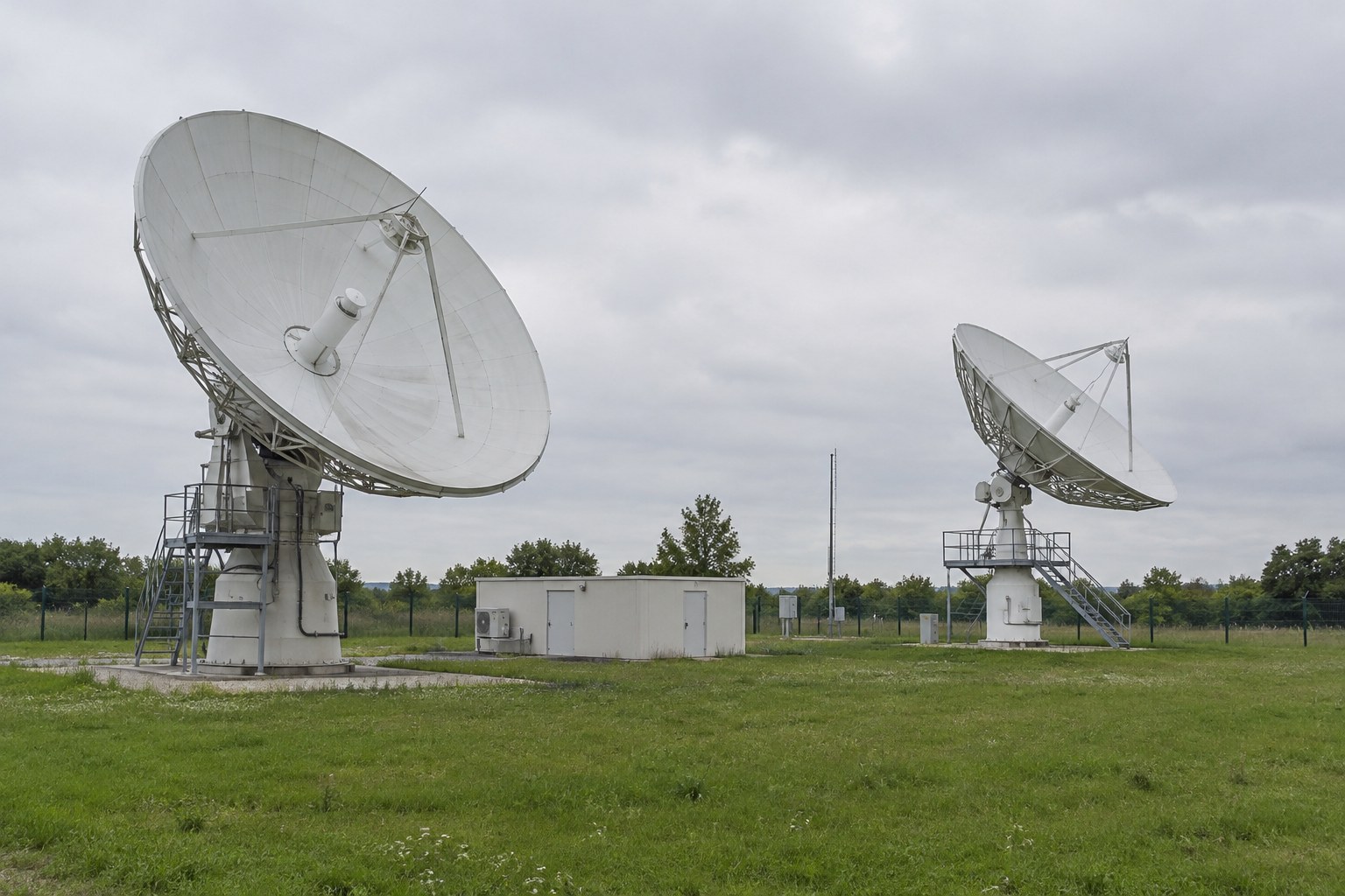Satellitenantenne einer Bodenstation unter bewölktem Himmel.