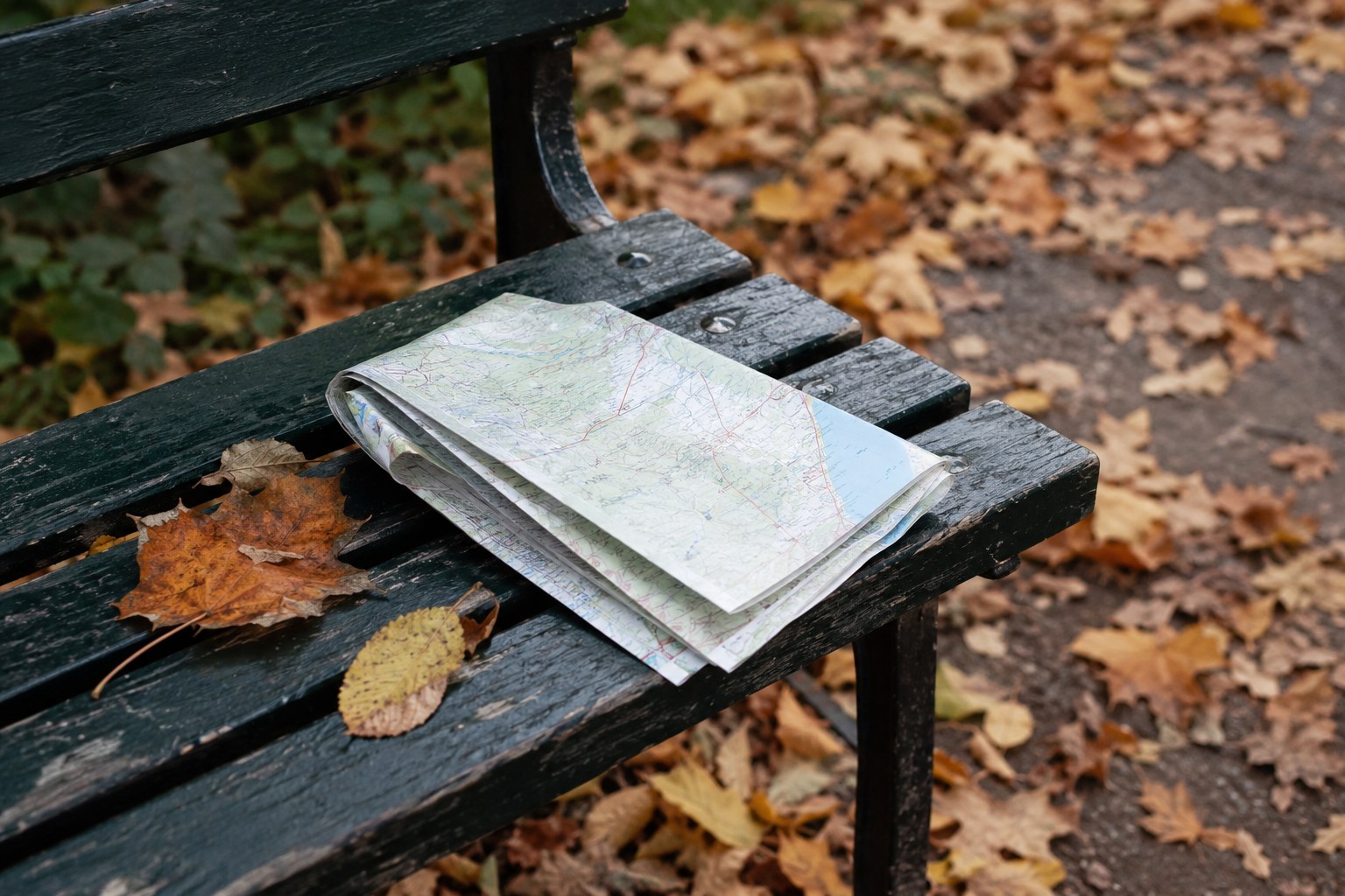 Eine gefaltete Karte liegt auf einer Parkbank.