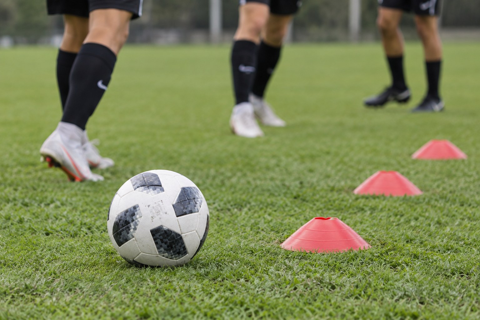 Ein Fußball liegt neben Markierungshütchen beim Training.