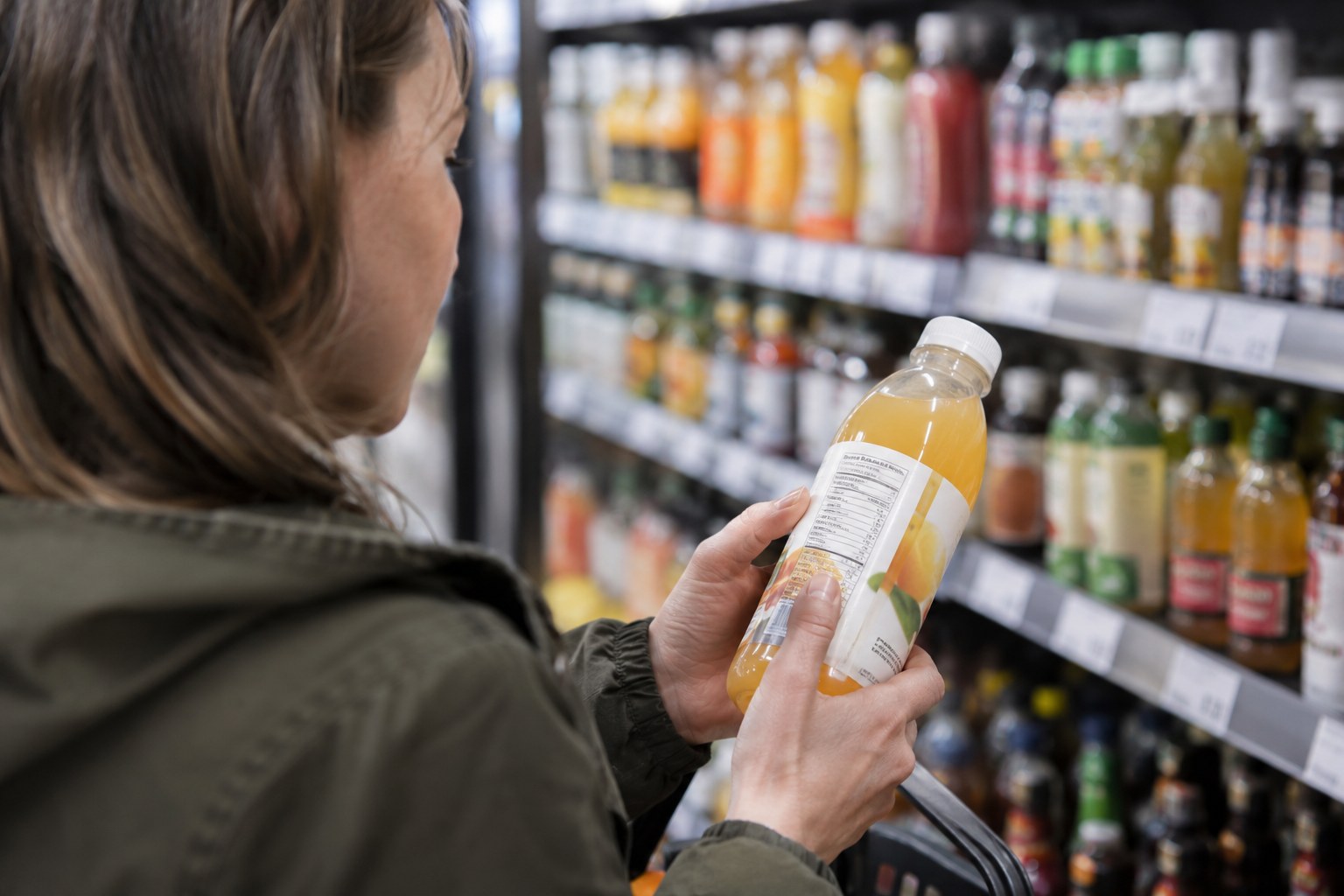Eine Kundin betrachtet die Nährwertangaben auf einer Flasche.