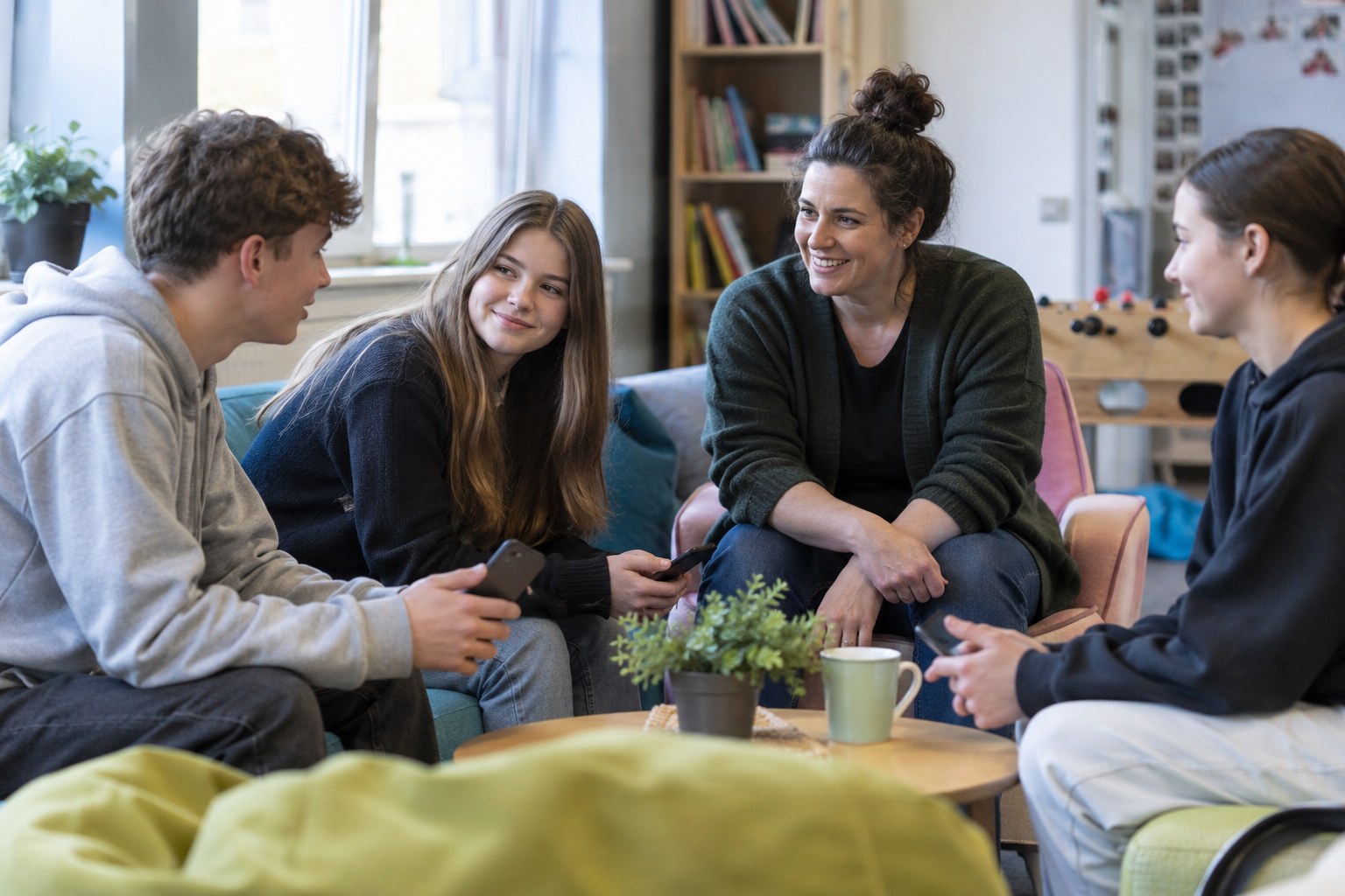 Jugendliche mit Smartphones sprechen mit einer Erwachsenen.