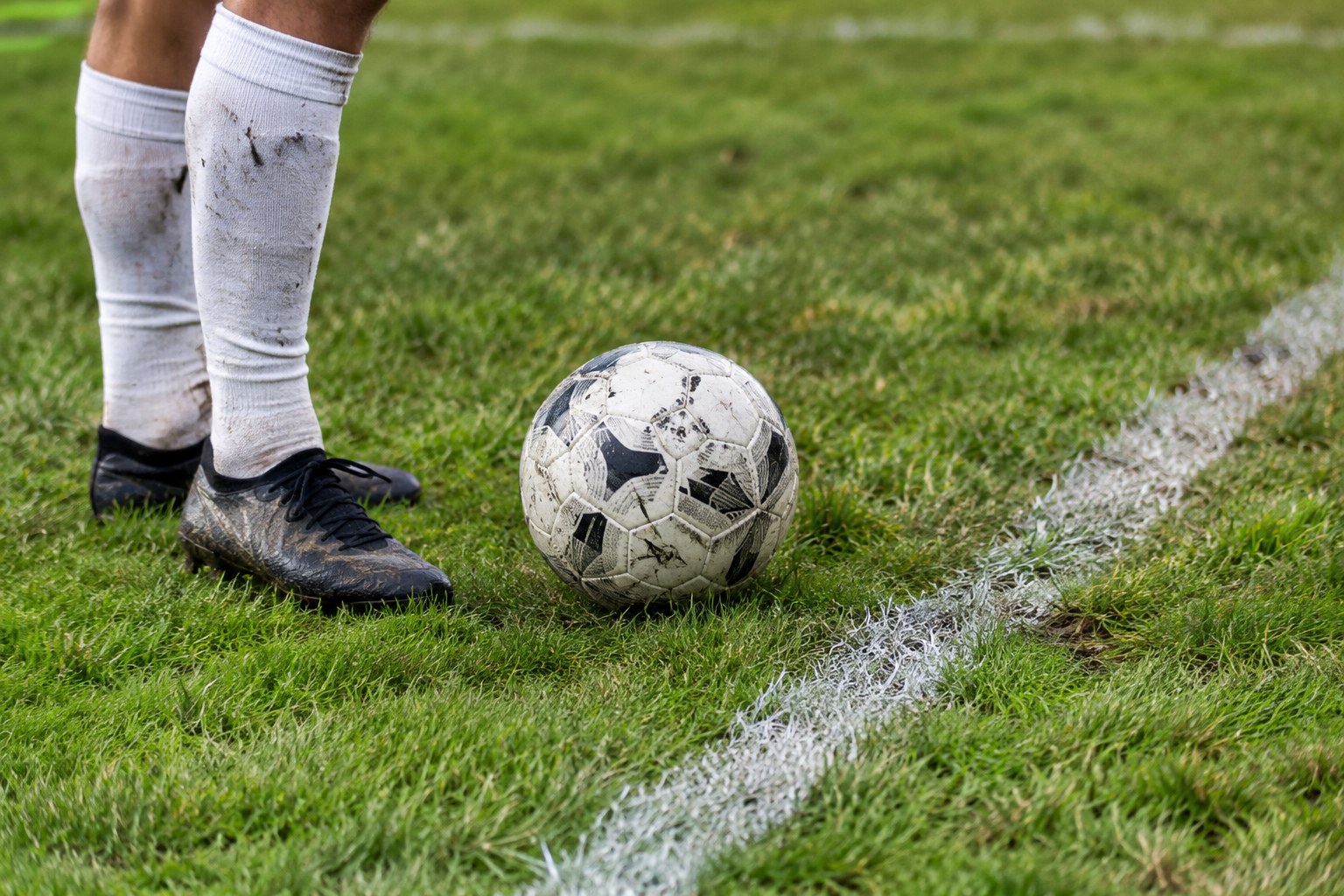 Fußballschuhe und Ball auf einem Rasenplatz.