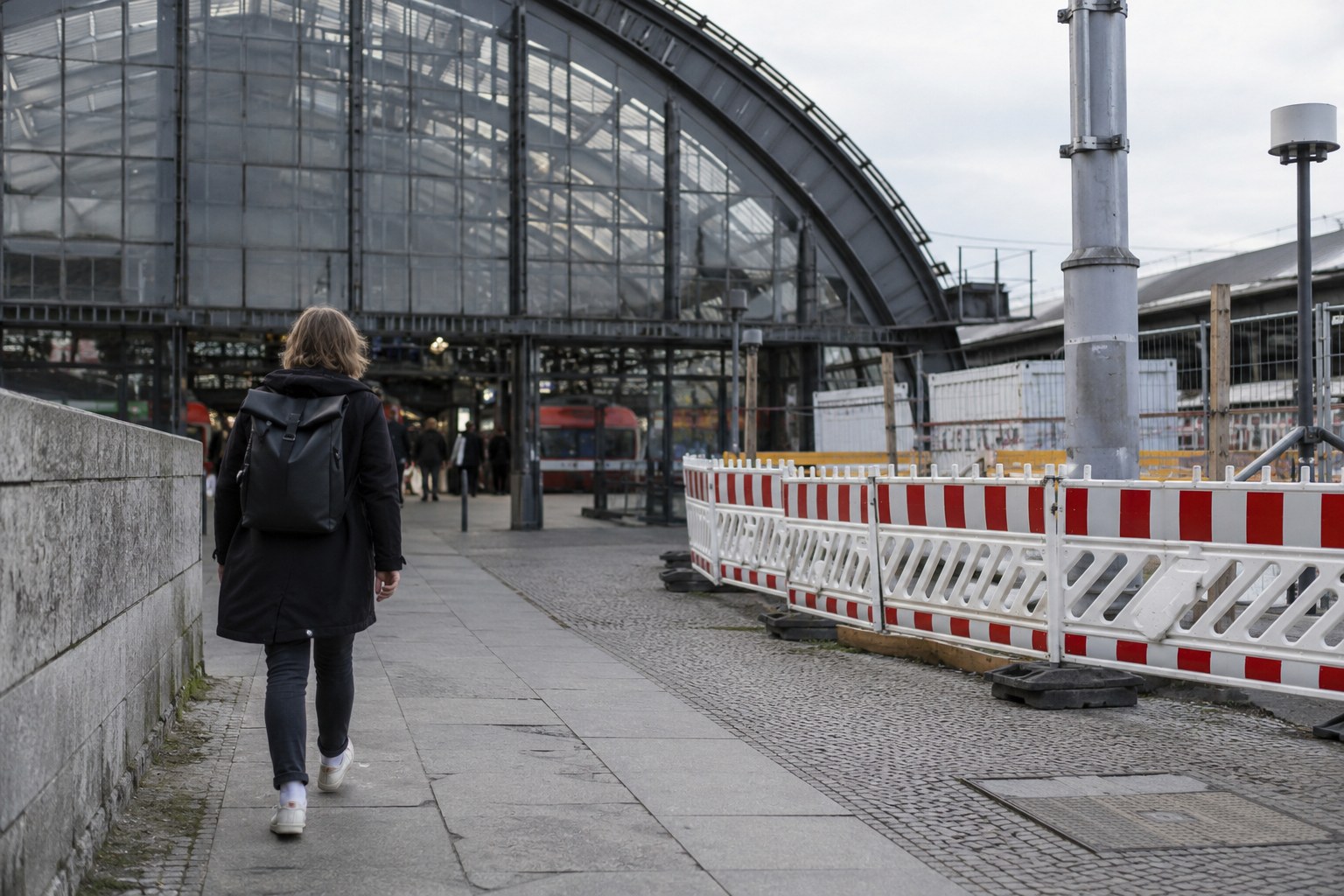 Eine Reisende geht an Absperrungen im Umfeld eines Bahnhofs vorbei.
