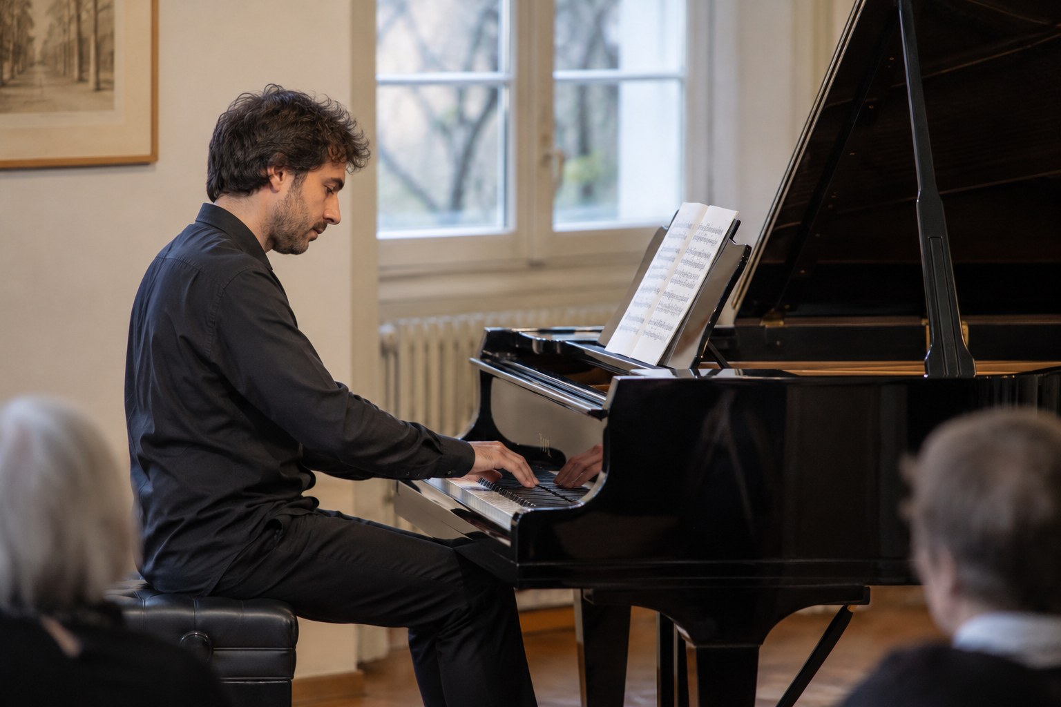 Ein Pianist spielt an einem Flügel in einem kleinen Konzertsaal.
