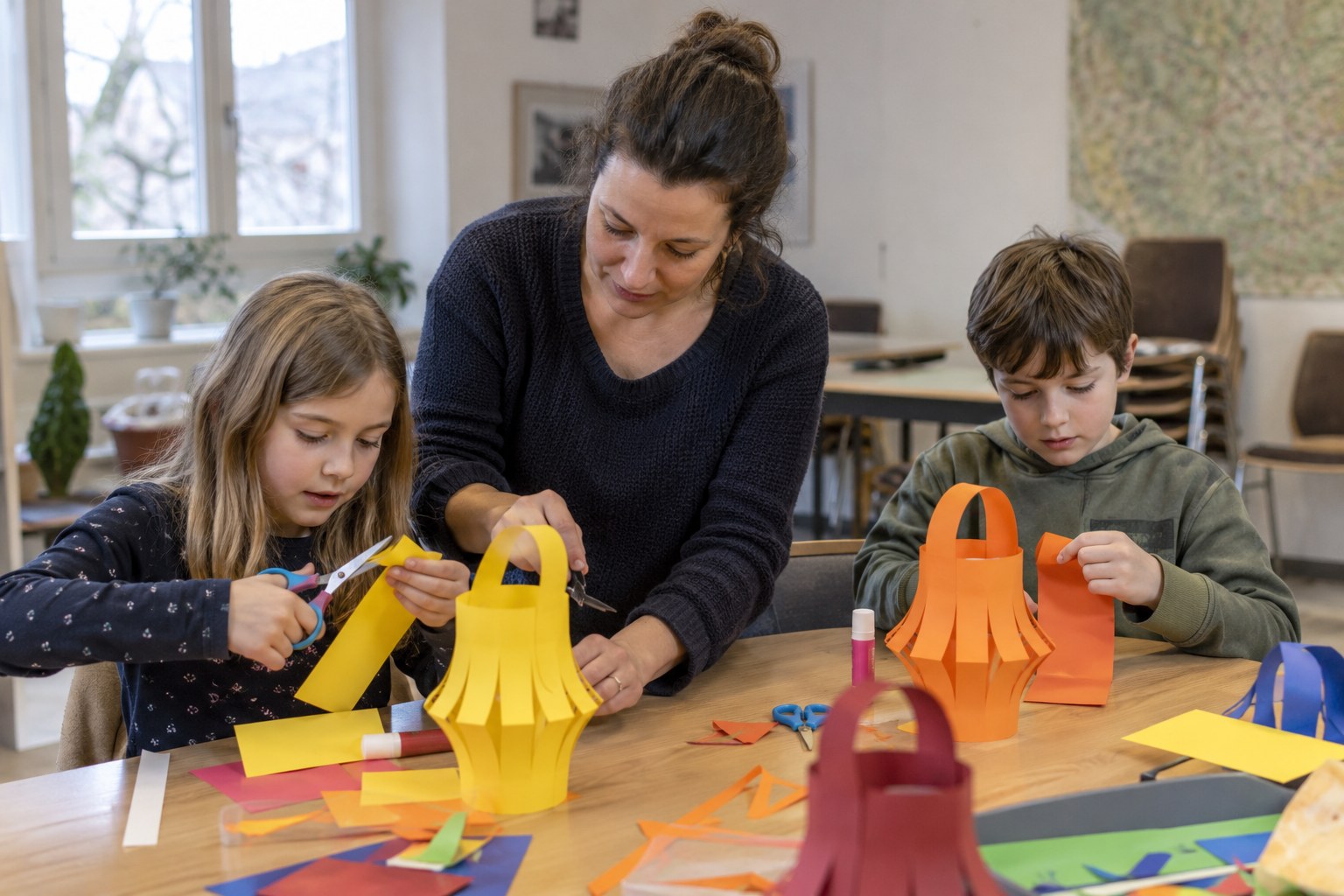 Eine Kursleiterin hilft Kindern beim Basteln von Papierlaternen.