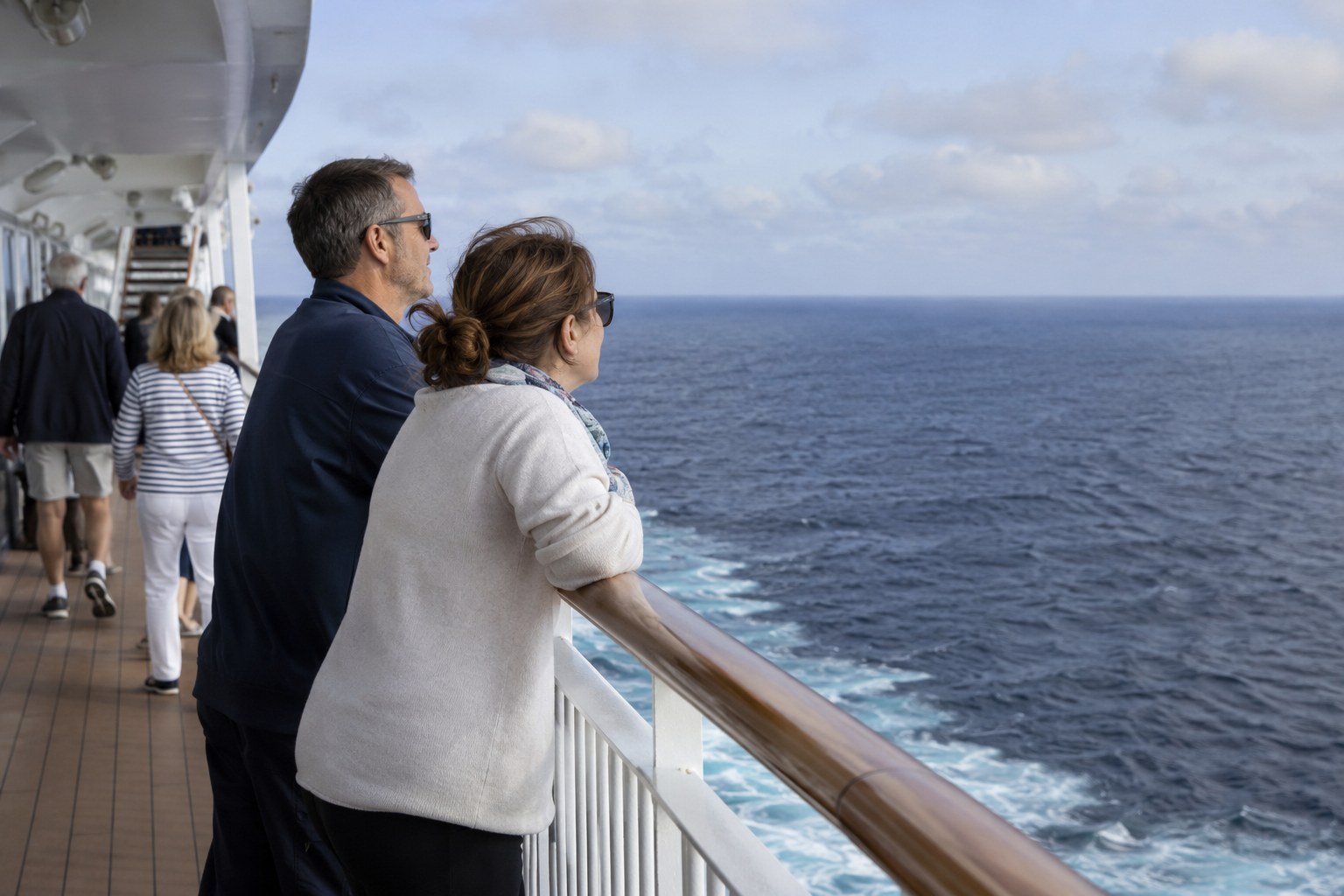 Passagiere schauen von einem Schiffsdeck aufs Meer.