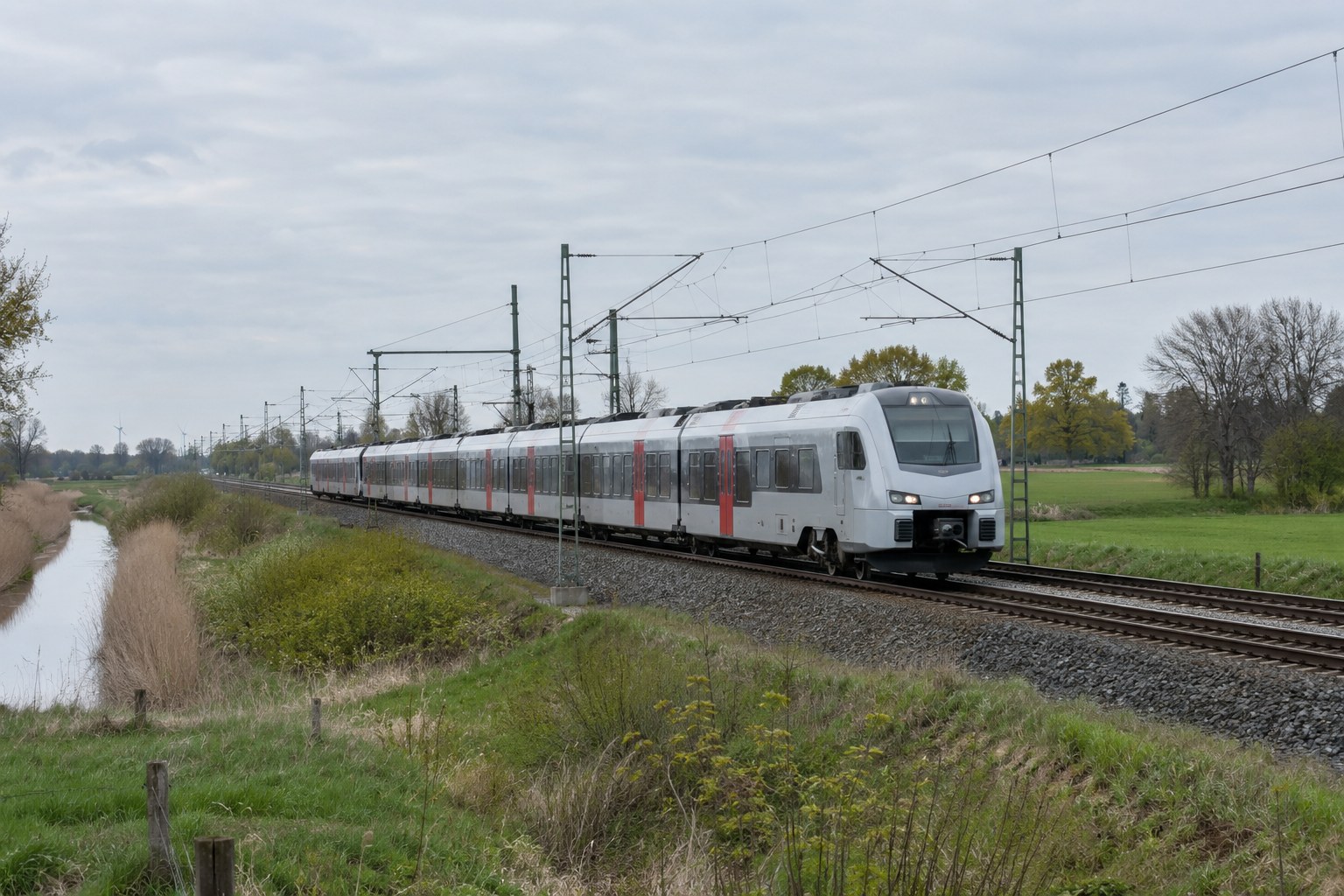 Personenzug auf einer elektrifizierten Bahnstrecke.