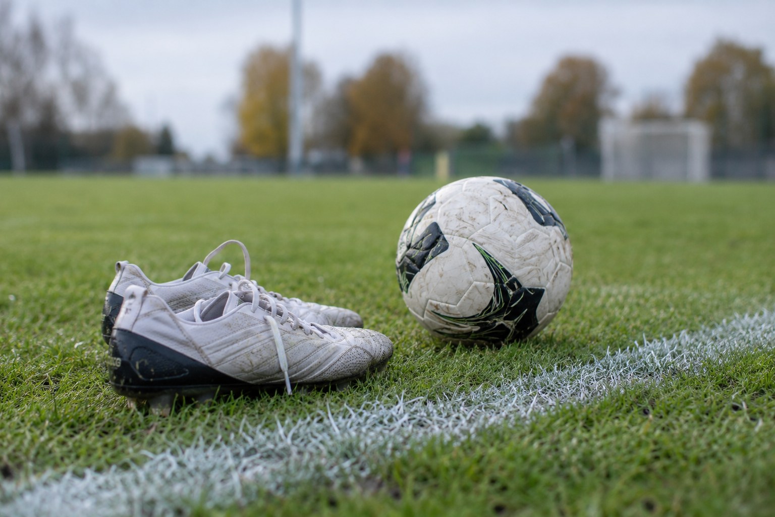 Fußballschuhe und Ball an einer Seitenlinie.