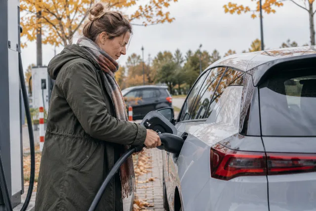 Eine Fahrerin verbindet ein Elektroauto mit einer Ladesäule.