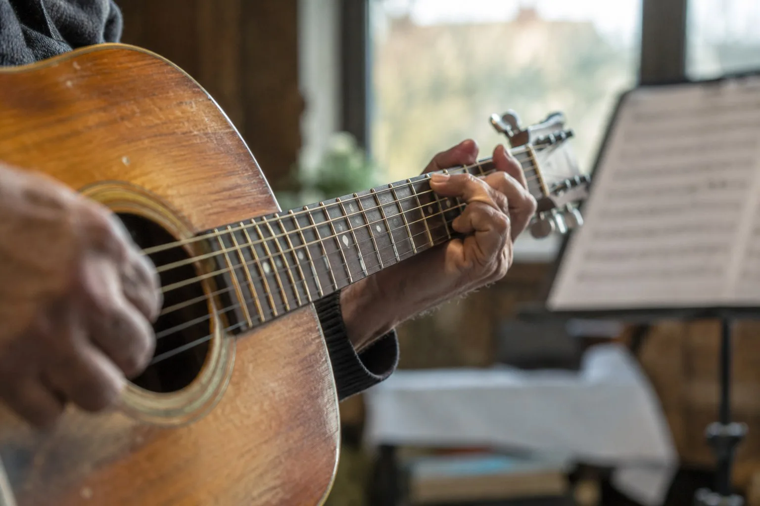 Nahaufnahme von Händen beim Spielen einer Akustikgitarre.