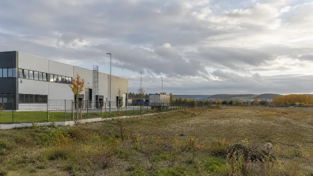KI-generiertes Symbolbild: Moderne Fabrikhalle neben freien Gewerbeflächen.